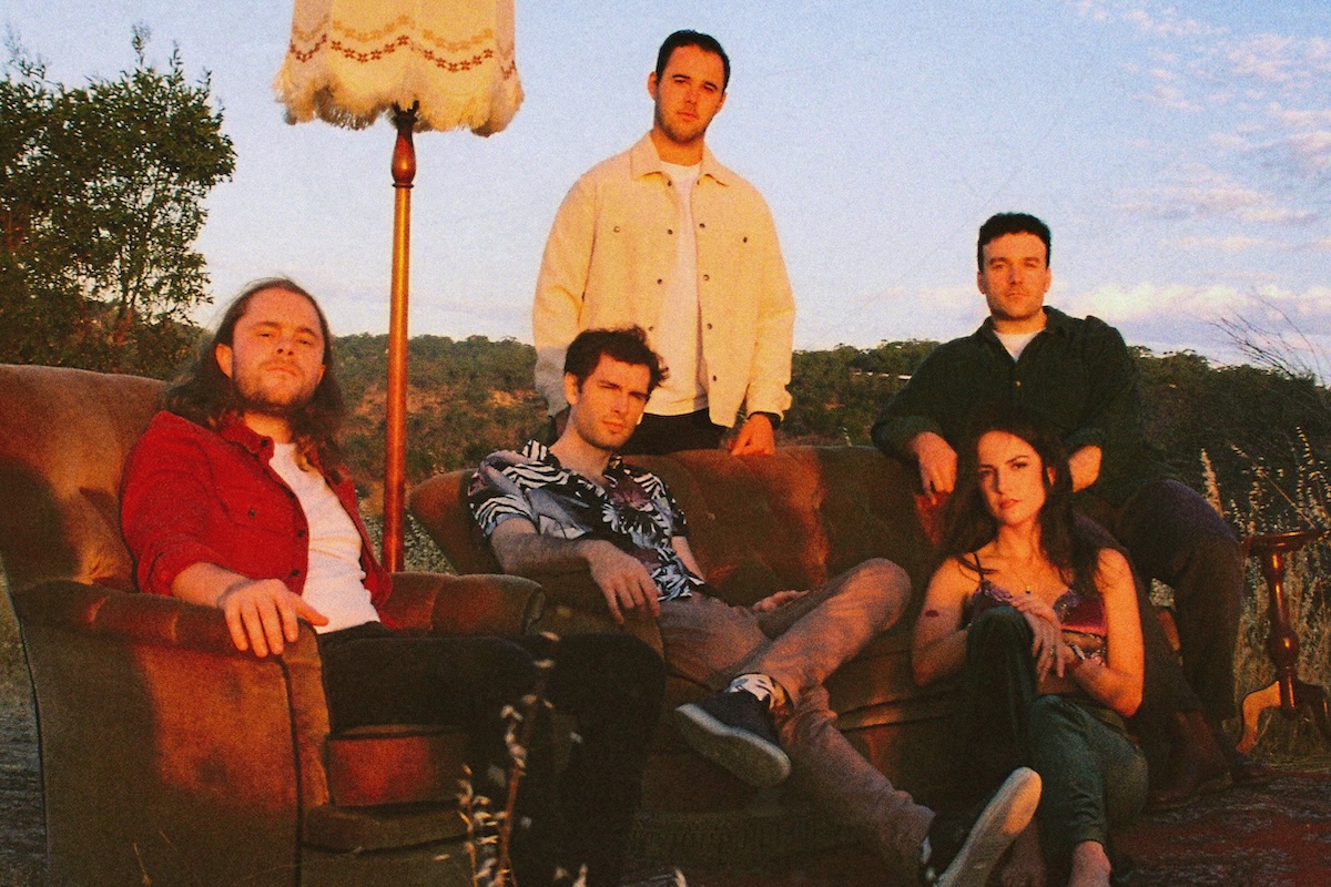 Five members of the band Sister Moonshine posing outdoors with couches and a vintage floor lamp at sunset.